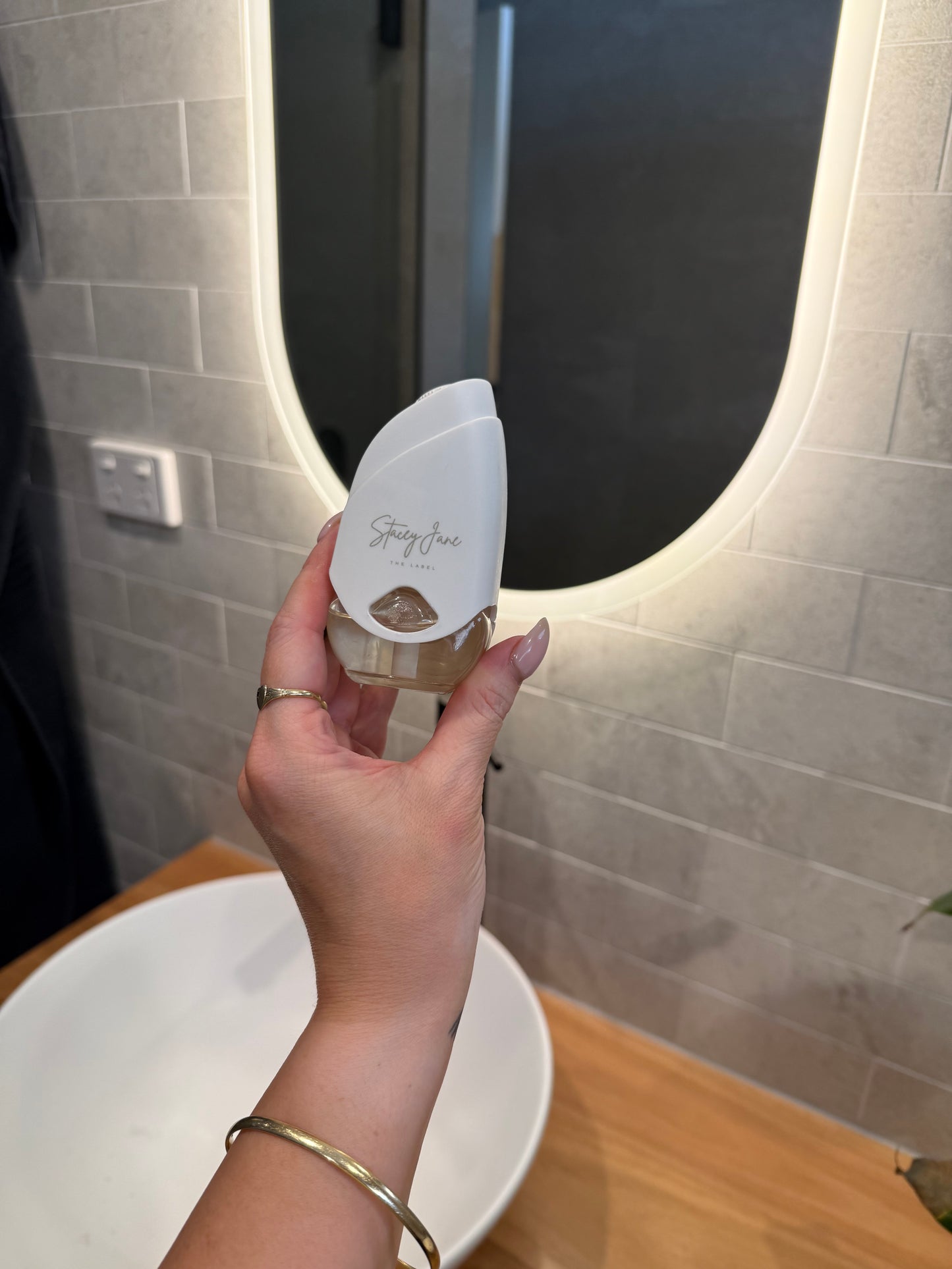 Stacey Jane 24/7 LUX Diffuser with sleek design and clear glass container, emitting gentle mist for aromatic diffusion.